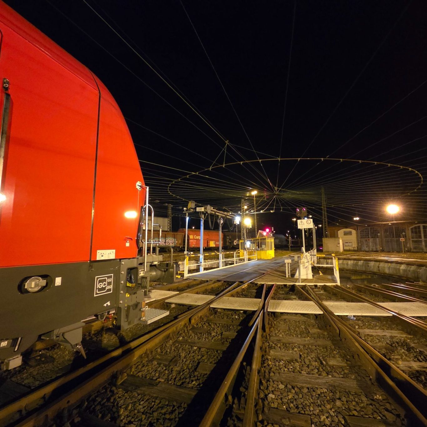 Drehscheide in Nürnberg Rangierbahnhof, bei Nacht Roten Zug an einem Bahnübergang bei Nacht mit beleuchtetem Hintergrund.